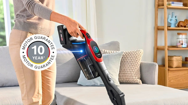 Red cordless Bosch Unlimited 10 ProAnimal stick vacuum with LED light cleaning carpet.