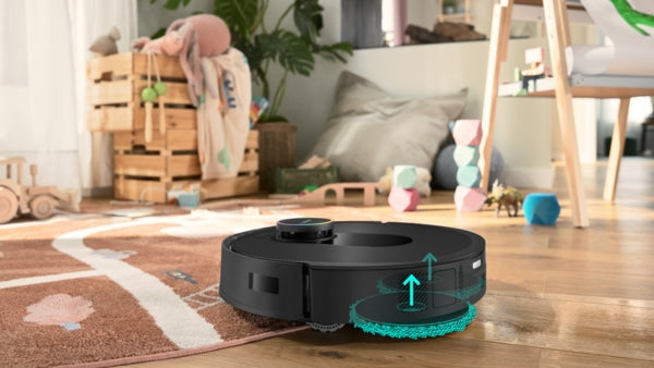 Black Bosch BCRDW3BX robot vacuum with turquoise mop pads cleaning hardwood floor in cozy living room.