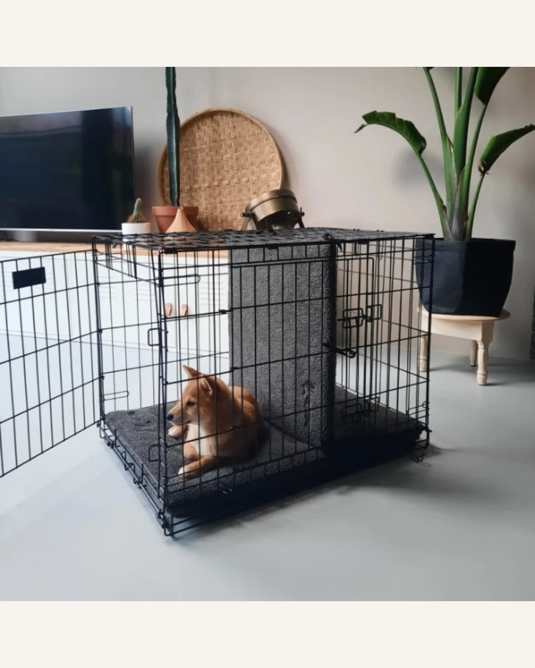 Black metal wire dog crate with gray soft Sherpa fleece bench divider inside, separating the space.