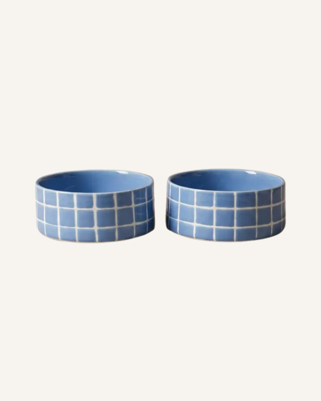 Two round blue ceramic pet bowls with white grid patterns and pale blue interiors.