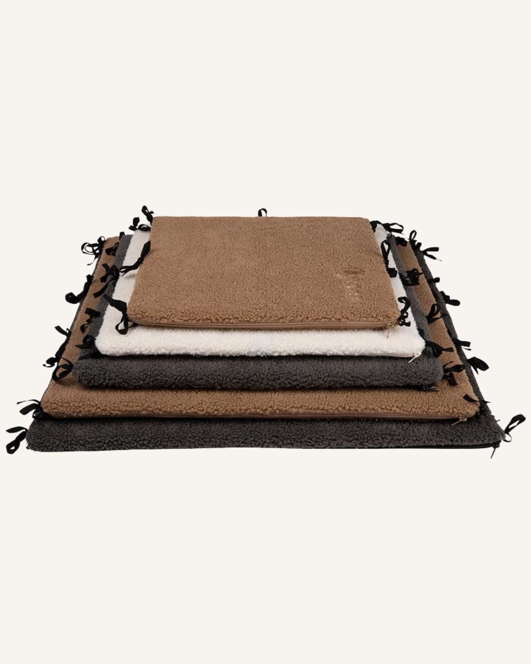 Stack of soft rectangular bench dividers in beige, white, brown, and dark gray with tie straps on edges.