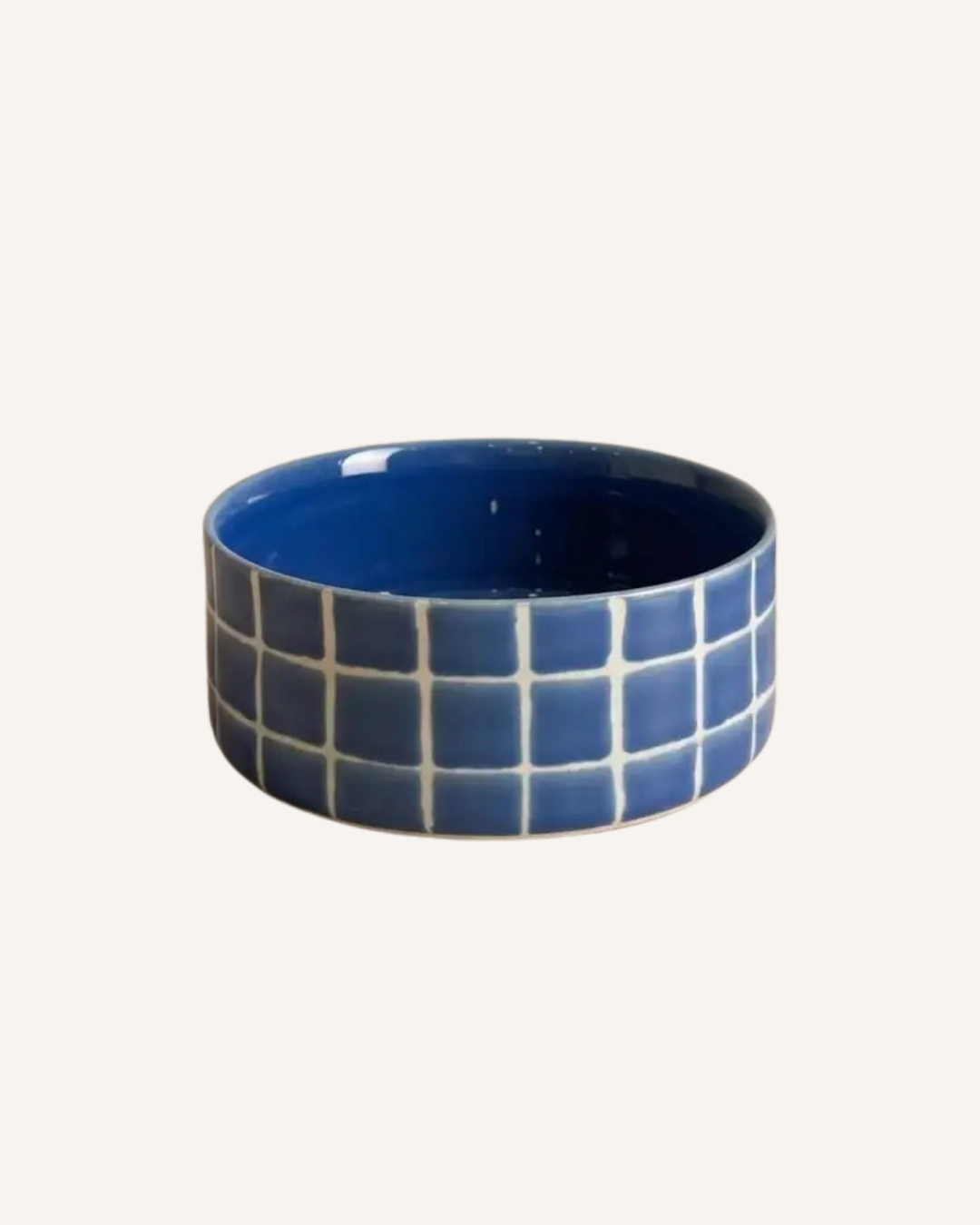 Round blue ceramic pet bowl with a glossy interior and a cream grid pattern around the outside.