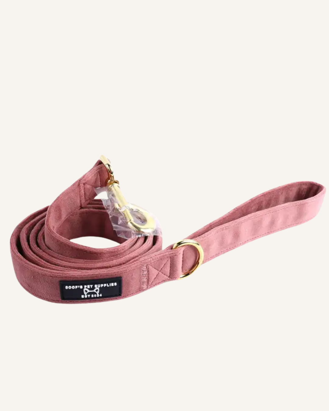 Dusty pink velvet dog leash with a gold-tone clasp and adjustable buckle, coiled beside its handle.