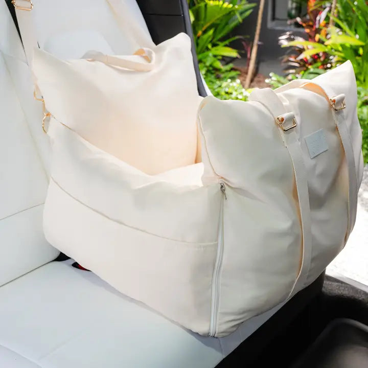 Beige premium pet car seat with sturdy sides and front strap buckle on a white car seat.
